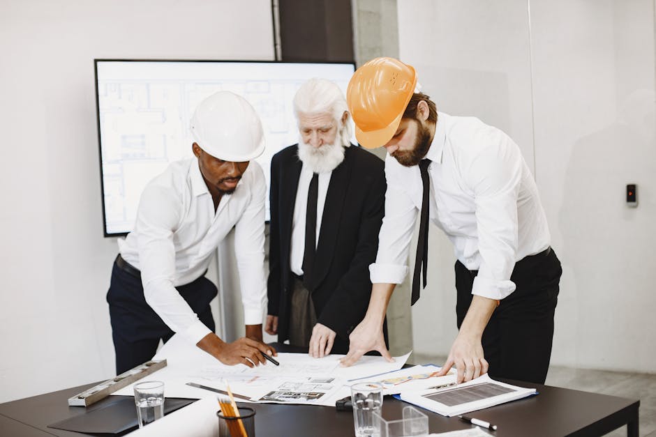 Three professionals in an office setting reviewing building plans and collaborating on a construction project