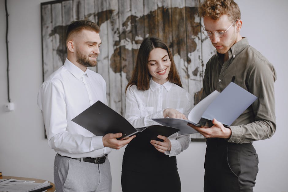 Three young professionals collaborating in an office, reviewing documents together with smiles and focus